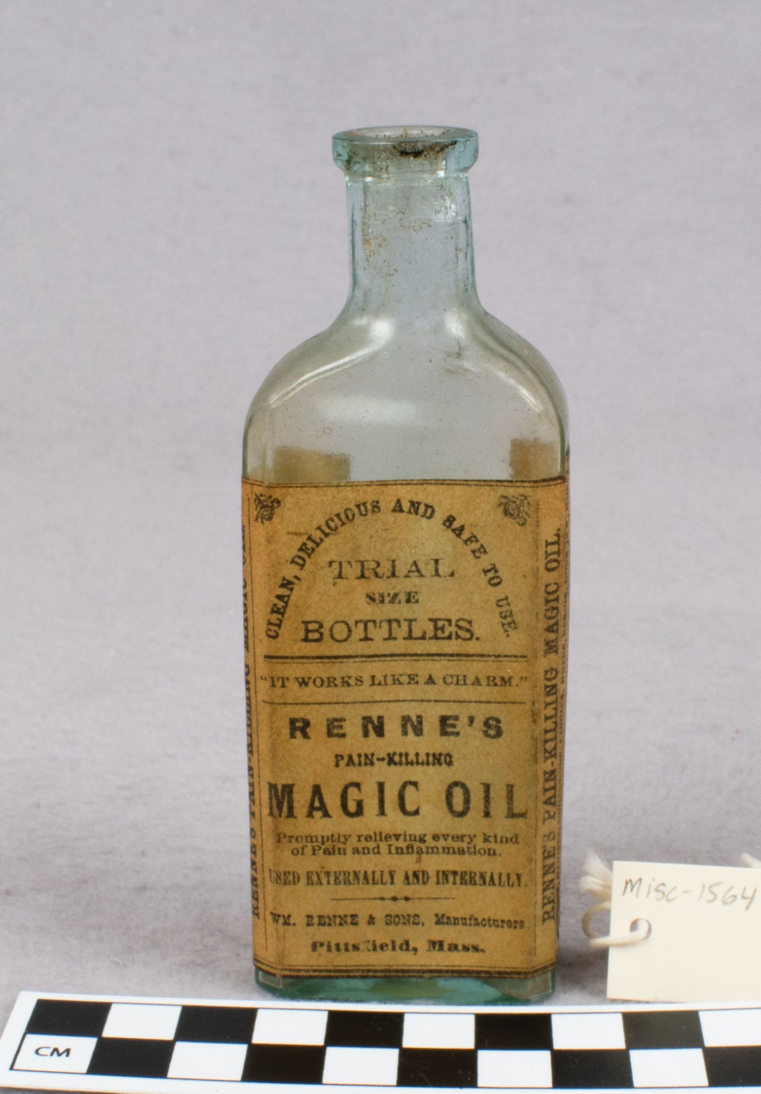 An old, empty glass bottle with a weathered brown paper label that says "Renne’s Pain-Killing Magic Oil"