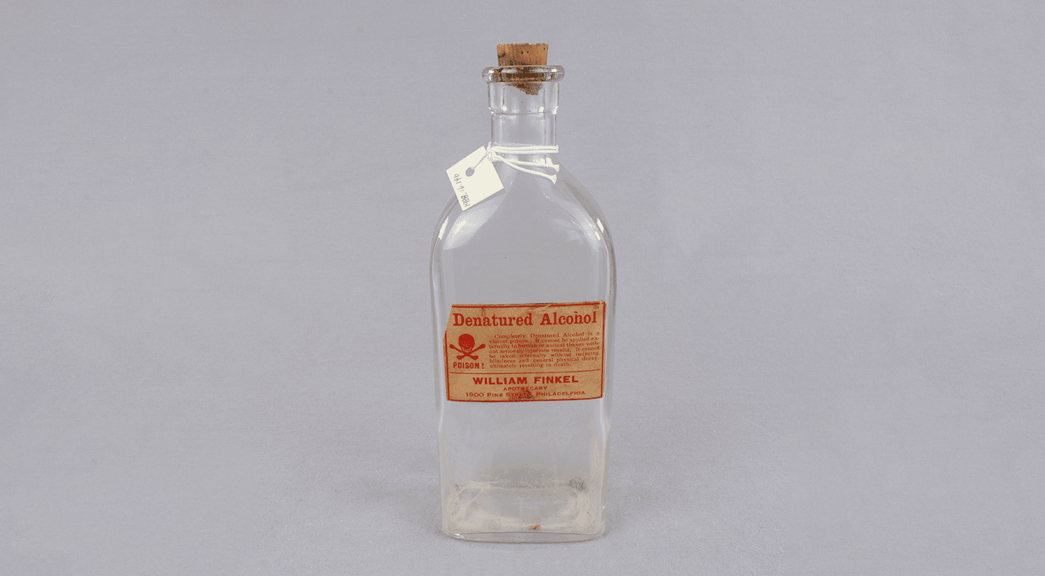 Empty bottle with tan and red label that says "Denatured alcohol"