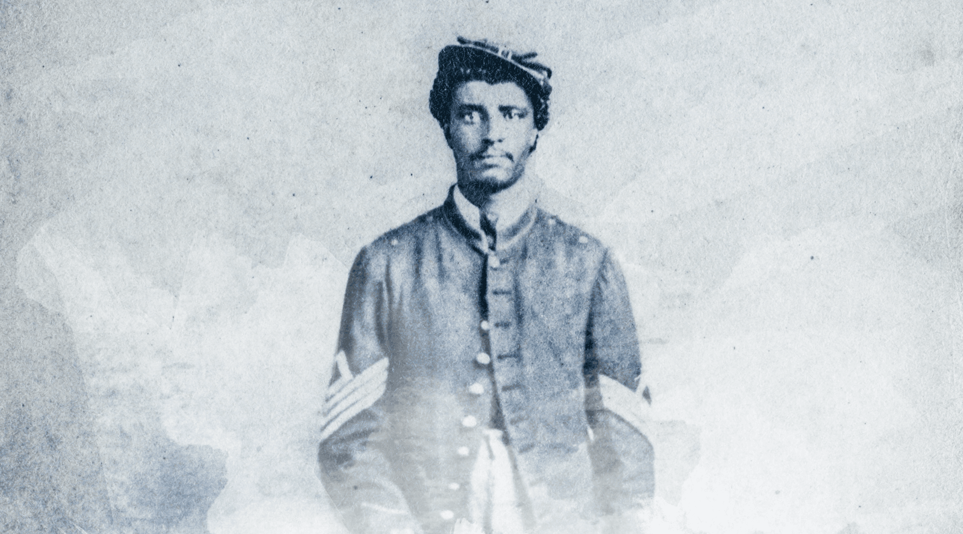 Blue, faded photograph of soldier in Civil War-era uniform and hat