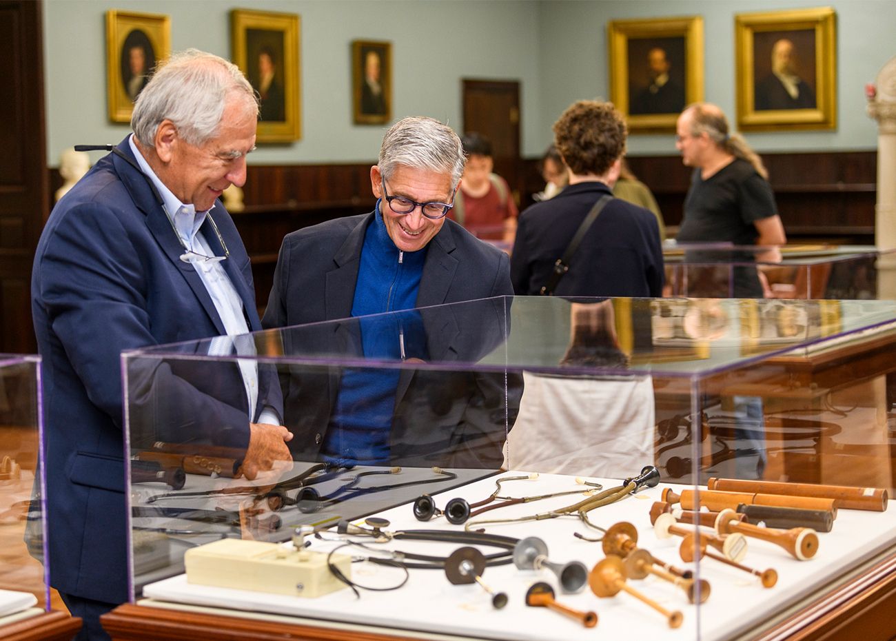 Two men standing over a glass case with an array of medical instruments laid out